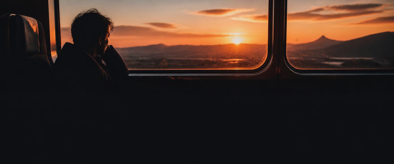 A traveller looking out of a train window in golden light