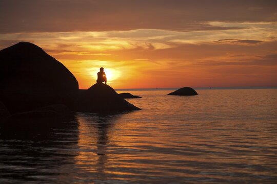 A traveller watching the sunset from the rocks at Palolem Beach, Goa